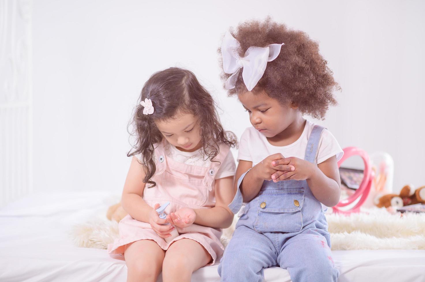 una simpatica ragazza per metà africana guarda il suo amico asiatico che gli preme del gel alcolico sulla mano per pulire e prevenire i germi foto