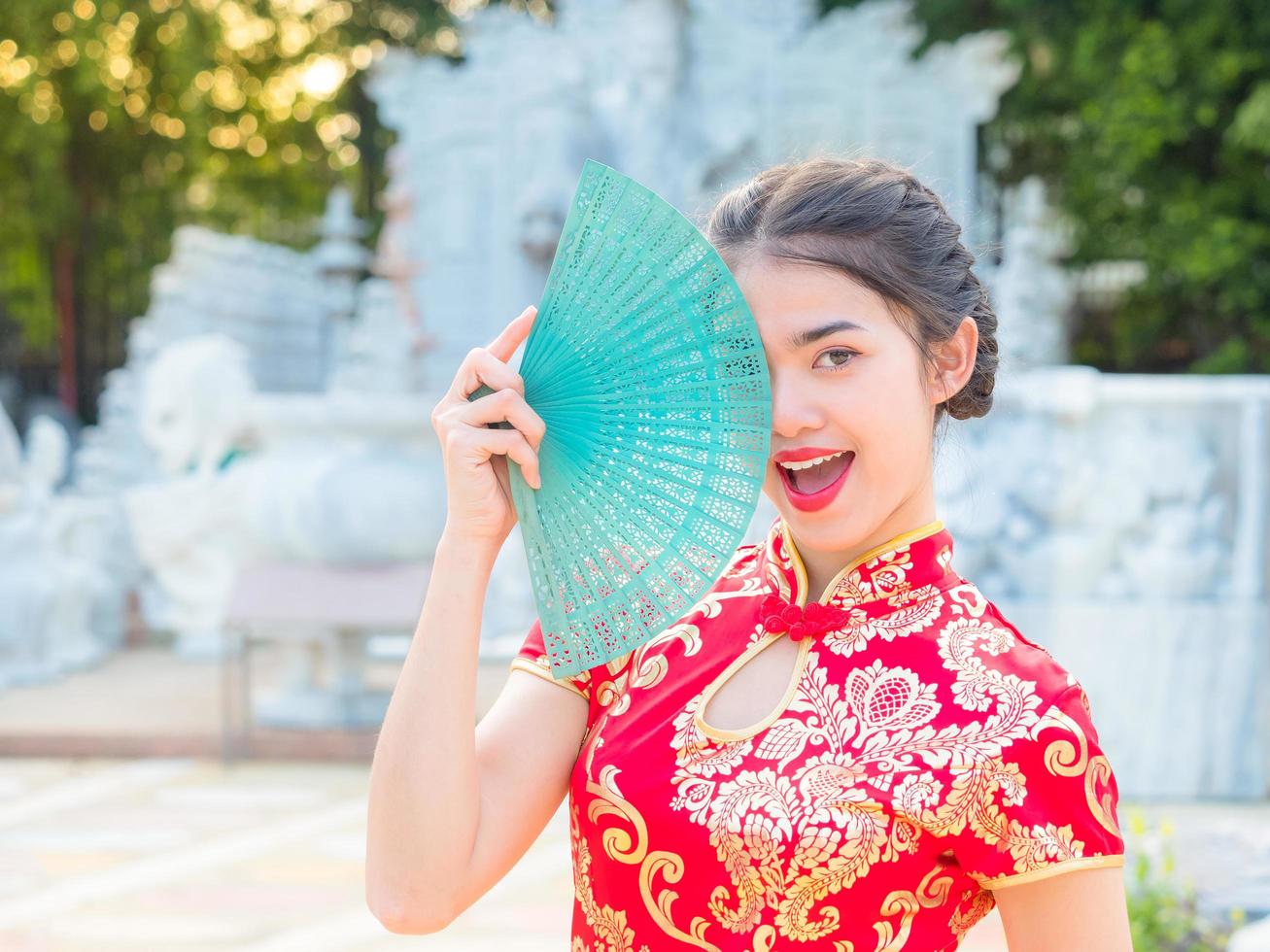 le donne asiatiche in costumi nazionali cinesi tengono un ventaglio di legno per l'evento del capodanno cinese foto