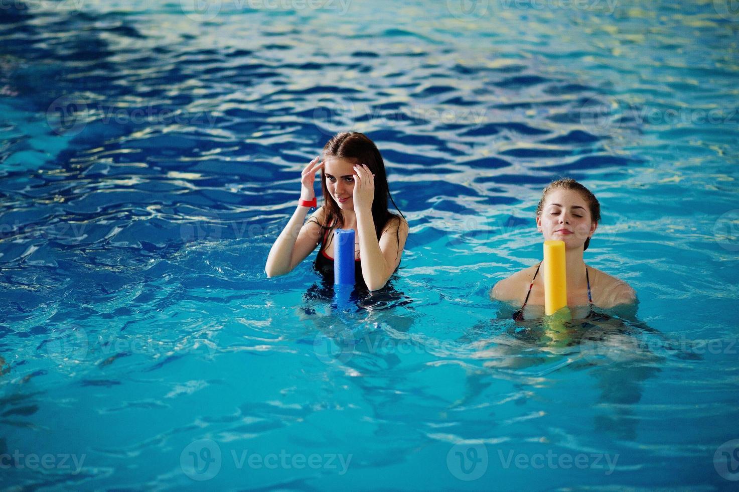 gruppo fitness di ragazze che fanno esercizi aerobici in piscina al parco acquatico. attività sportive e ricreative. foto