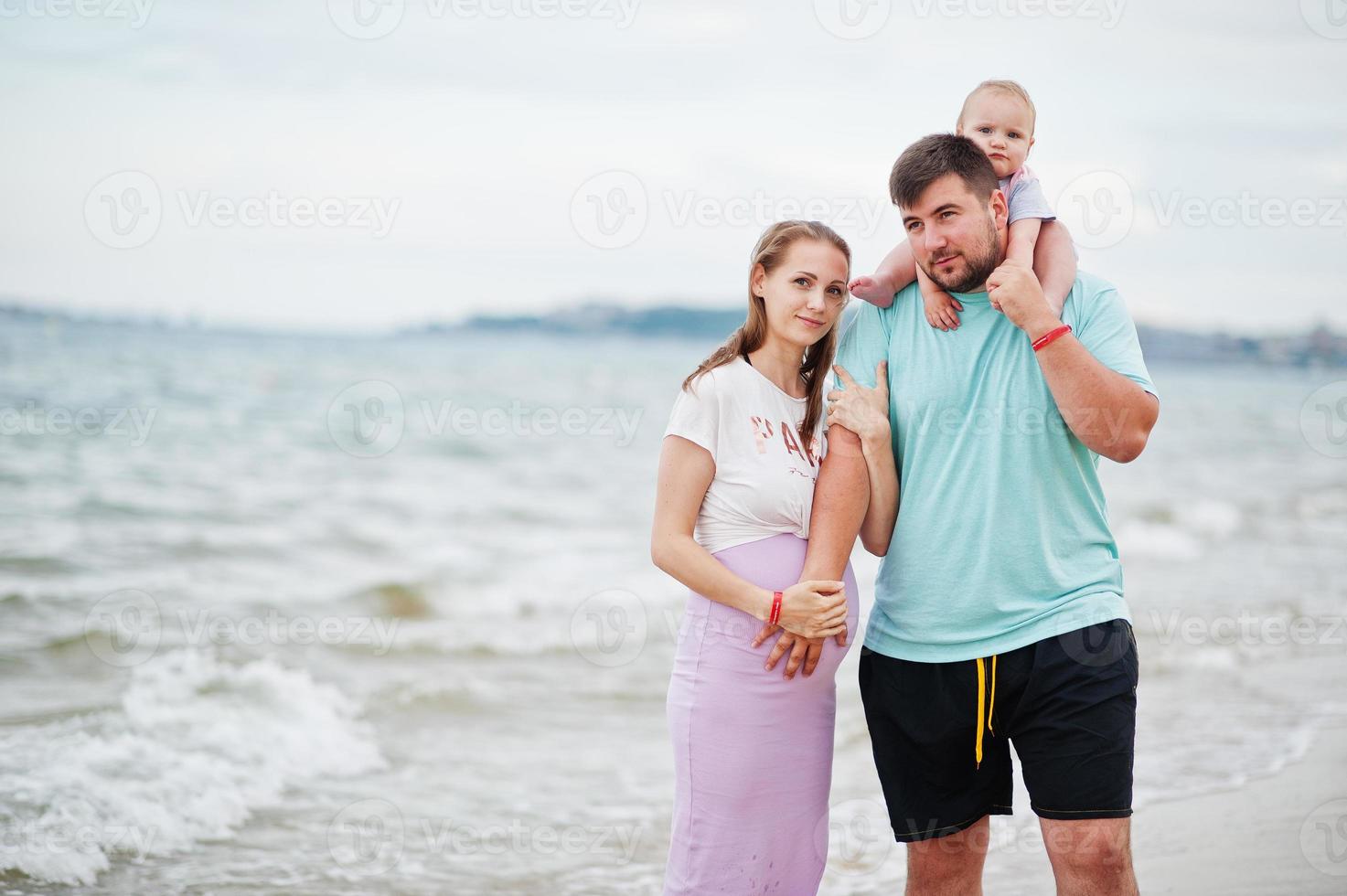 vacanze estive. genitori e persone attività all'aperto con i bambini. buone vacanze in famiglia. padre, madre incinta, figlia sulla spiaggia di sabbia del mare. foto