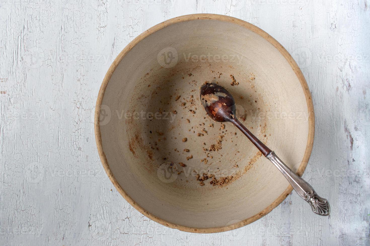 ciotola vuota di coccio di campagna con cucchiaio di legno e briciole rimanenti distese foto