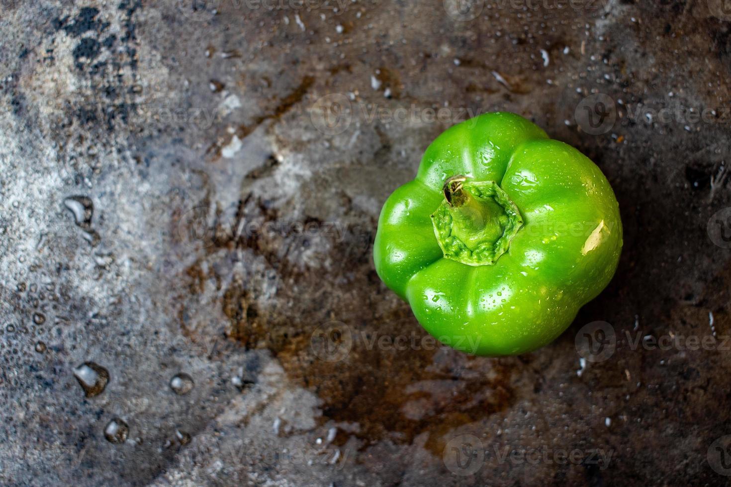 peperone verde isolato su fondo bagnato di metallo scuro piatto foto