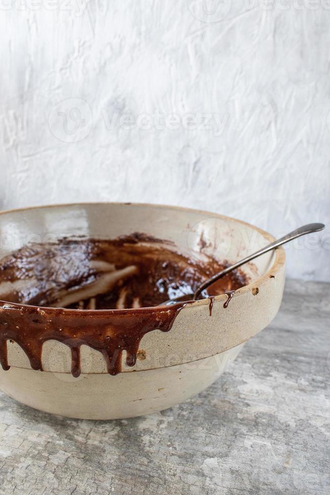 ciotola della fattoria e cucchiaio con i resti della miscela di brownie che gocciolano sul lato della ciotola foto