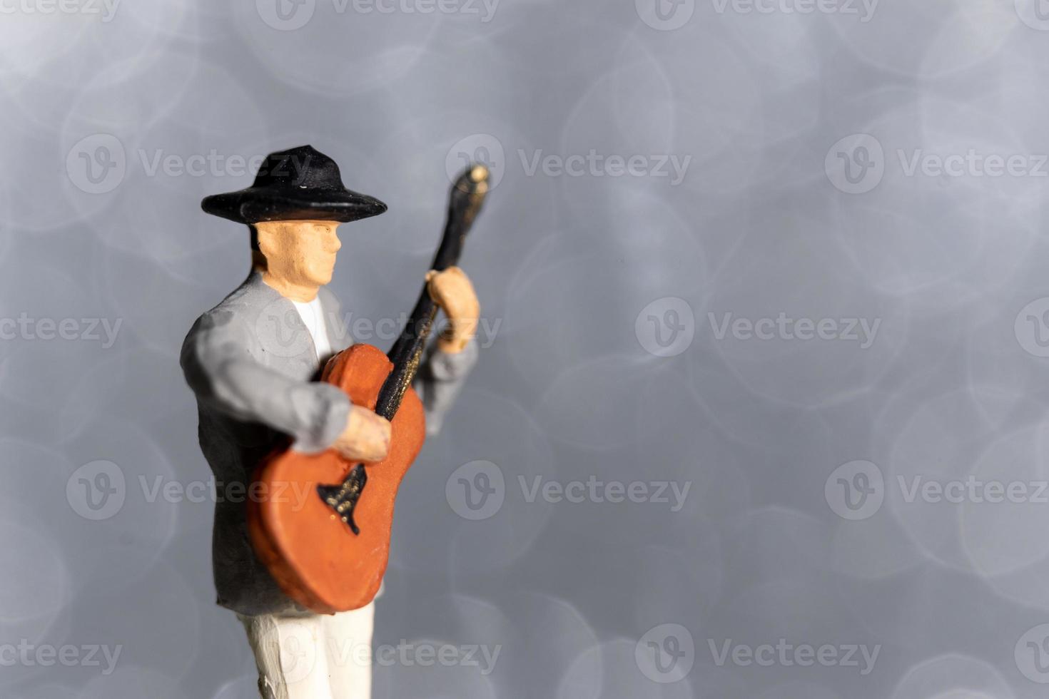 musicista in miniatura con la chitarra su sfondo bokeh foto