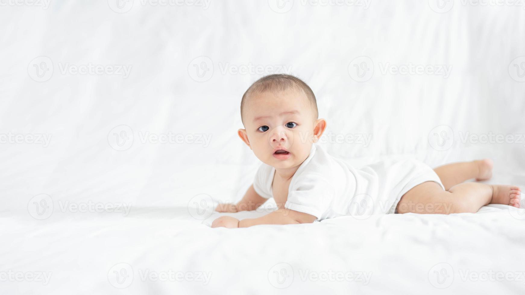 famiglia felice, carino asiatico neonato ragazzo sdraiato giocare sul letto bianco guardare la fotocamera con ridere sorriso faccia felice. piccolo innocente neonato adorabile bambino nel primo giorno di vita. concetto di festa della mamma. foto