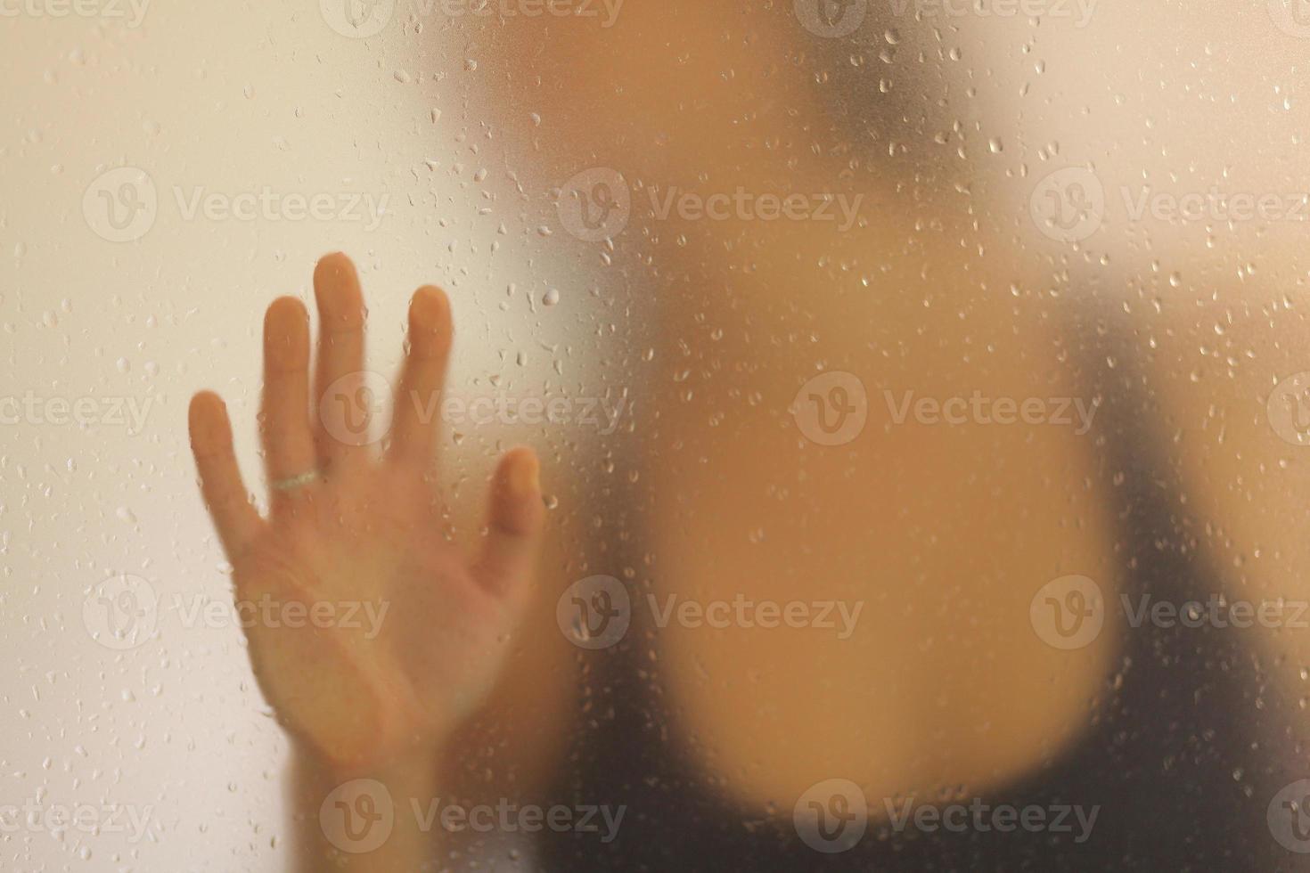 vista di una donna irriconoscibile che mette la mano dietro un vetro smerigliato foto