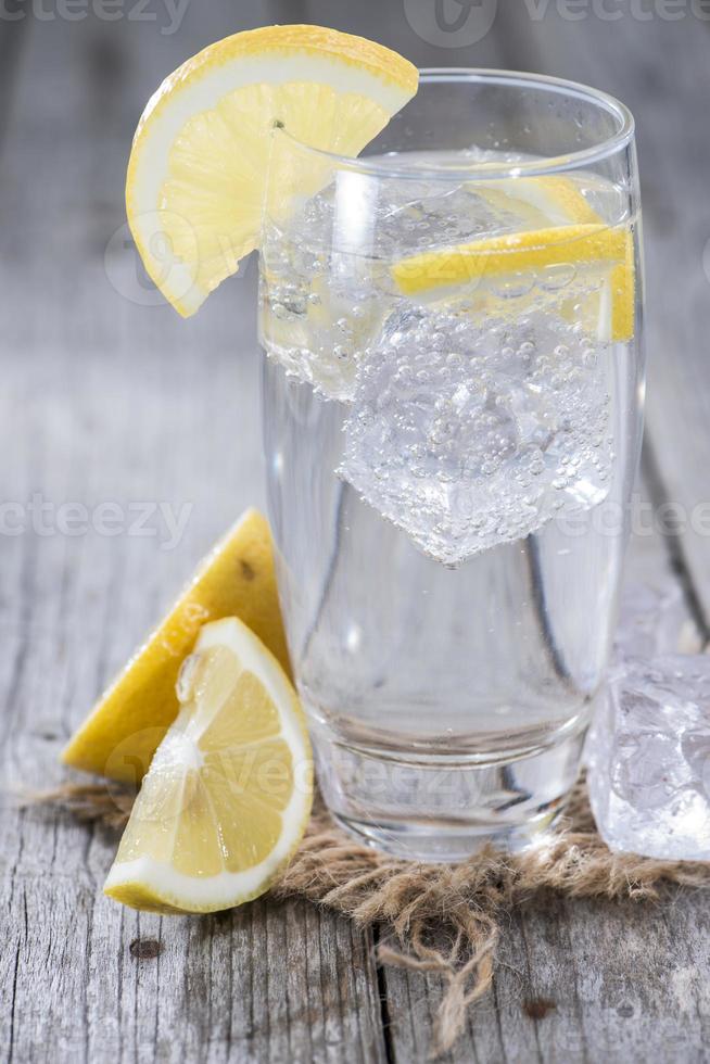 un bicchiere alto di acqua frizzante con spicchi di limone foto