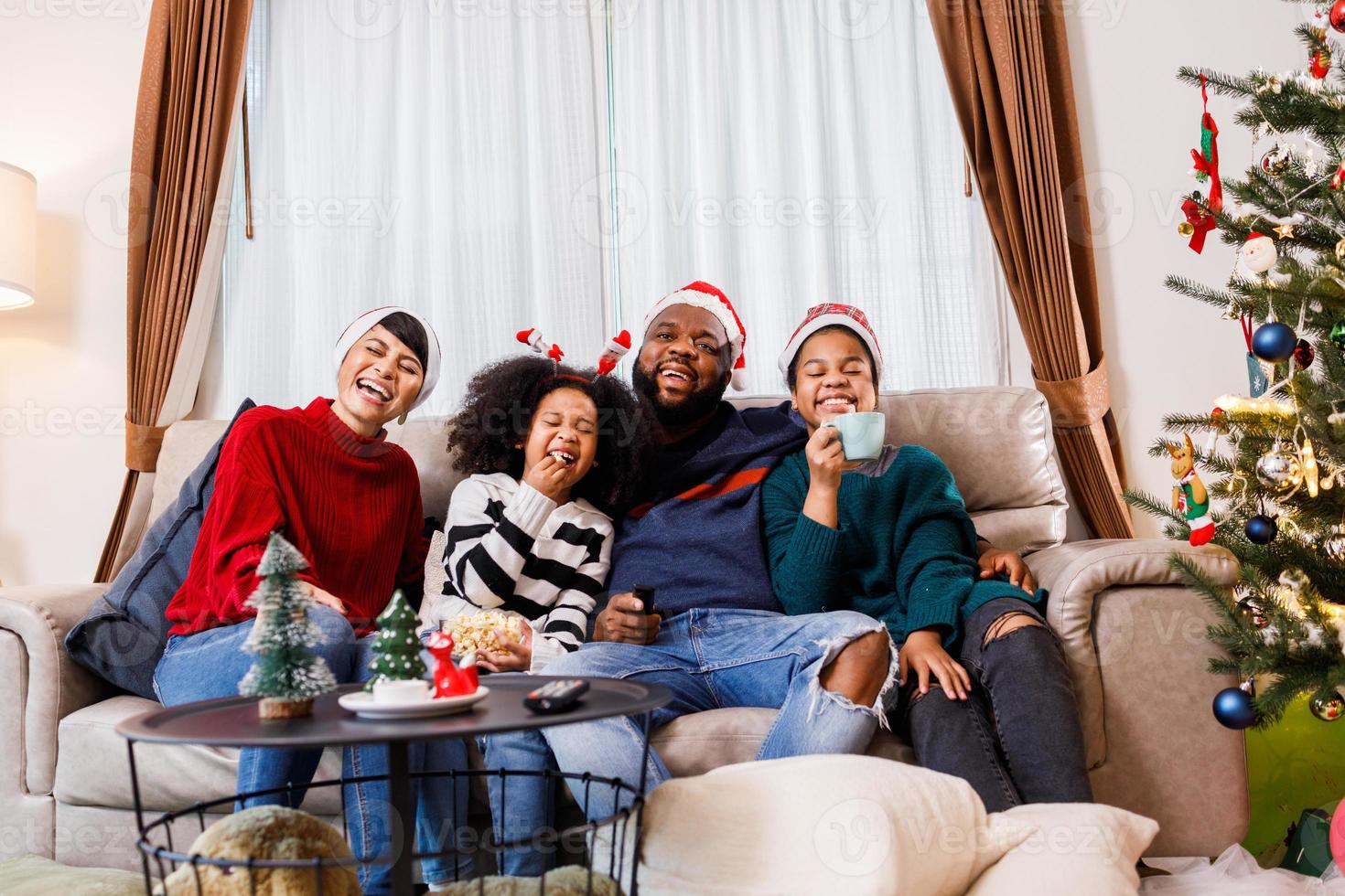 famiglia afroamericana in tema natalizio. la famiglia felice si diverte a sedersi insieme sul divano di casa. foto