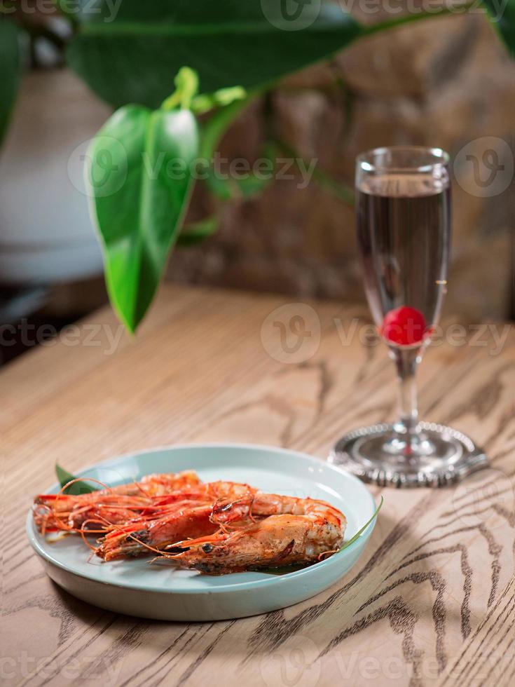 gamberetti sul piatto e cocktail alcolico kir petillant sul tavolo del bar foto
