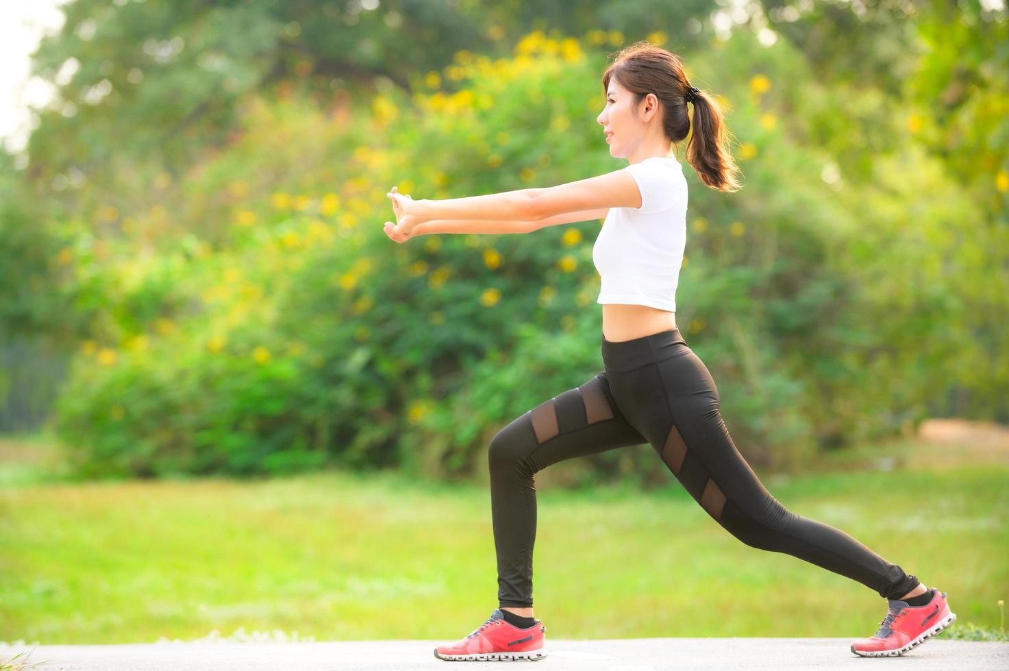 una bella donna asiatica si sta riscaldando, per rendere flessibili i muscoli prima di andare a fare jogging foto