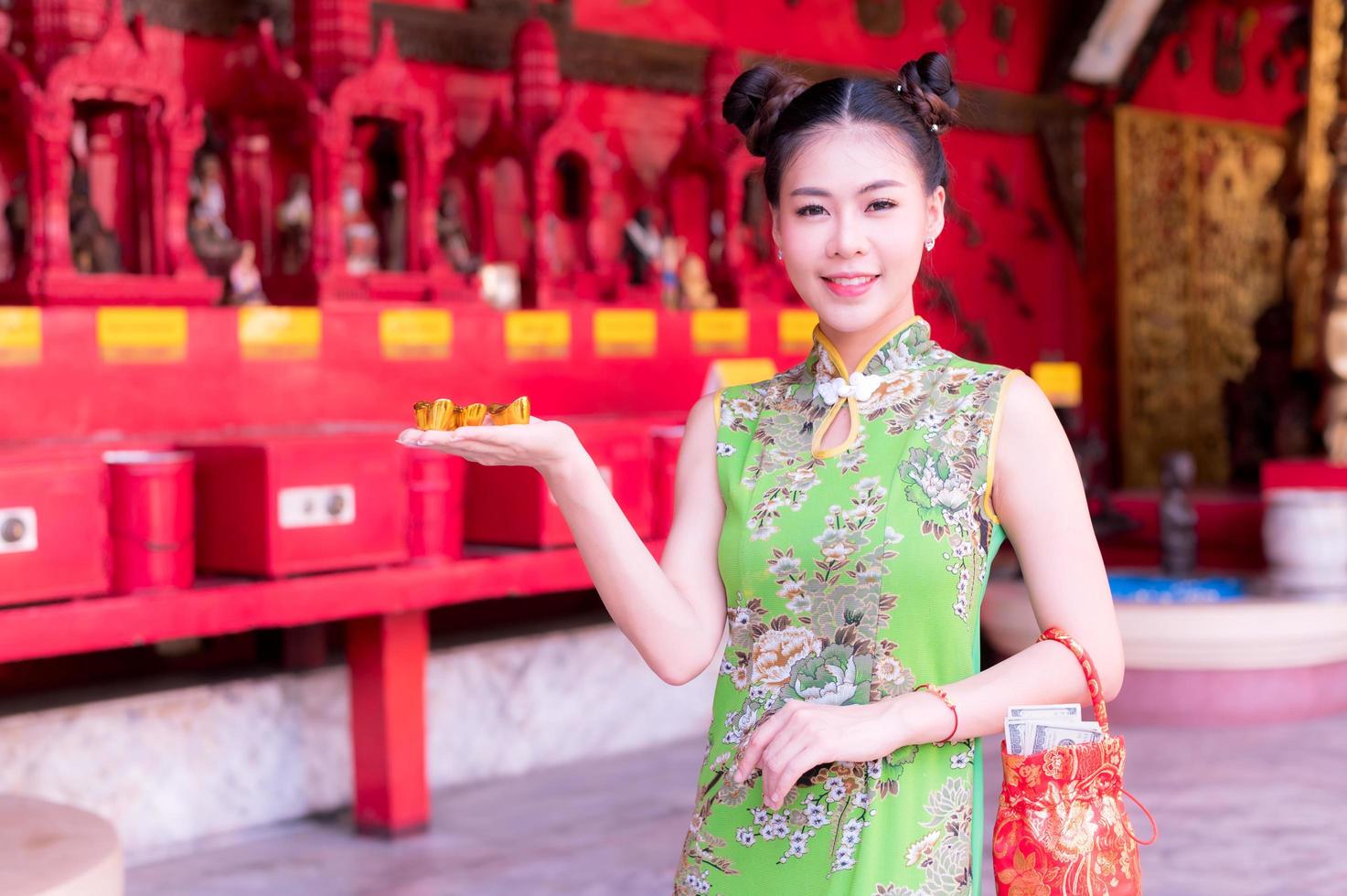 donna asiatica in costumi nazionali cinesi detiene un oro fortunato per l'evento del capodanno cinese foto