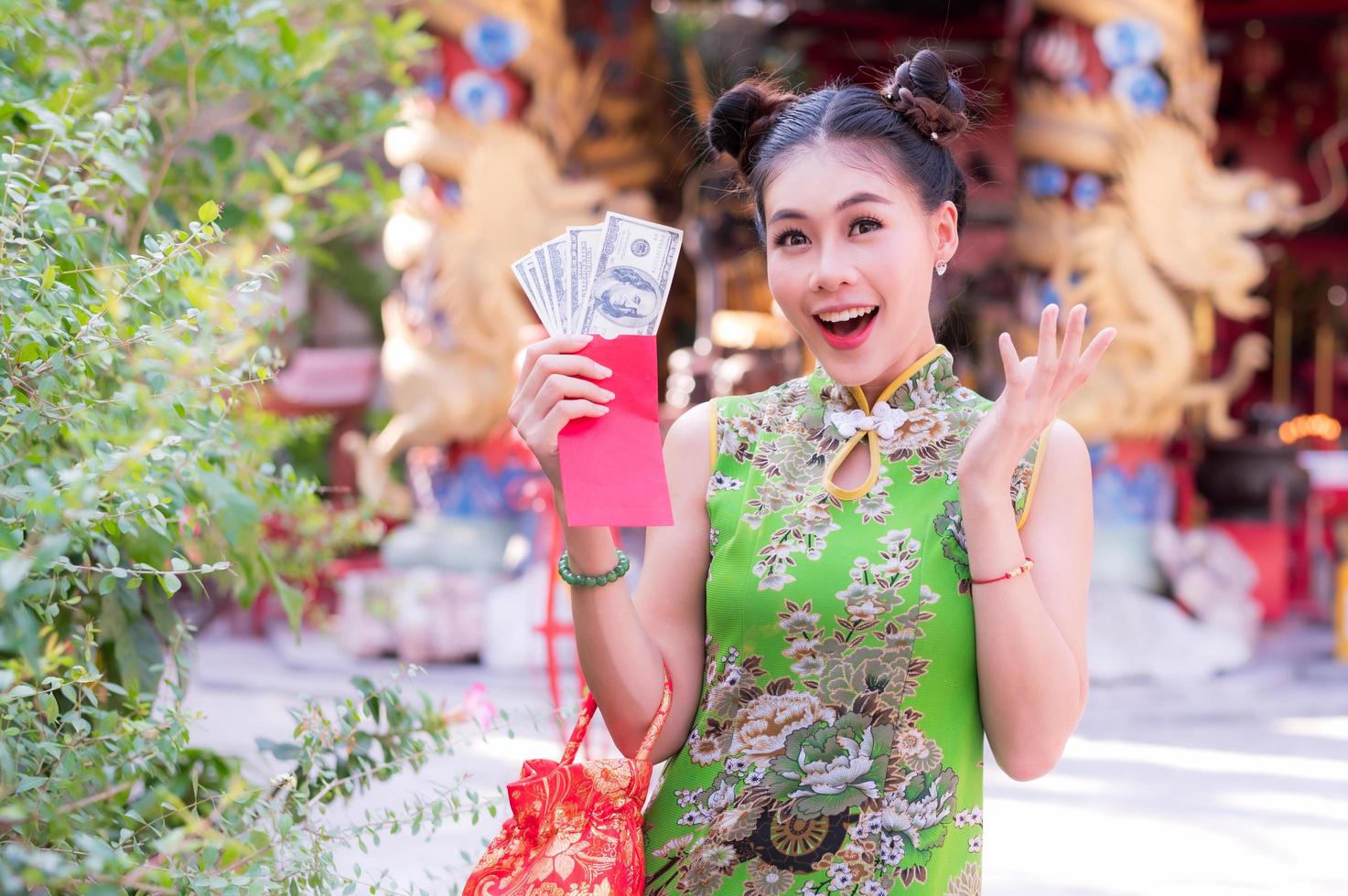 la donna asiatica in costumi nazionali cinesi tiene un denaro per l'evento del capodanno cinese foto