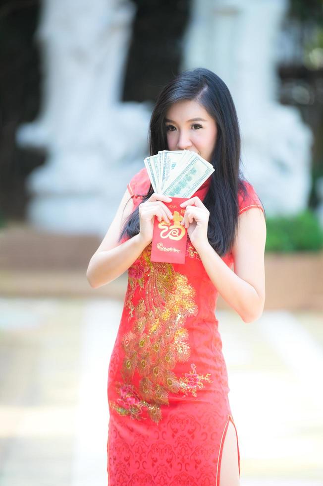 la donna asiatica in costumi nazionali cinesi tiene un denaro per l'evento del capodanno cinese foto