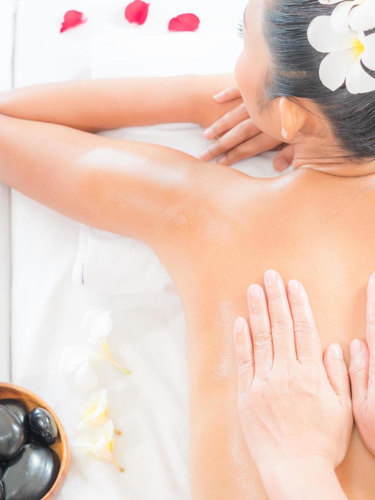 una massaggiatrice esperta in un salone termale mette le mani sulla schiena di una donna asiatica per alleviare la tensione dal lavoro foto