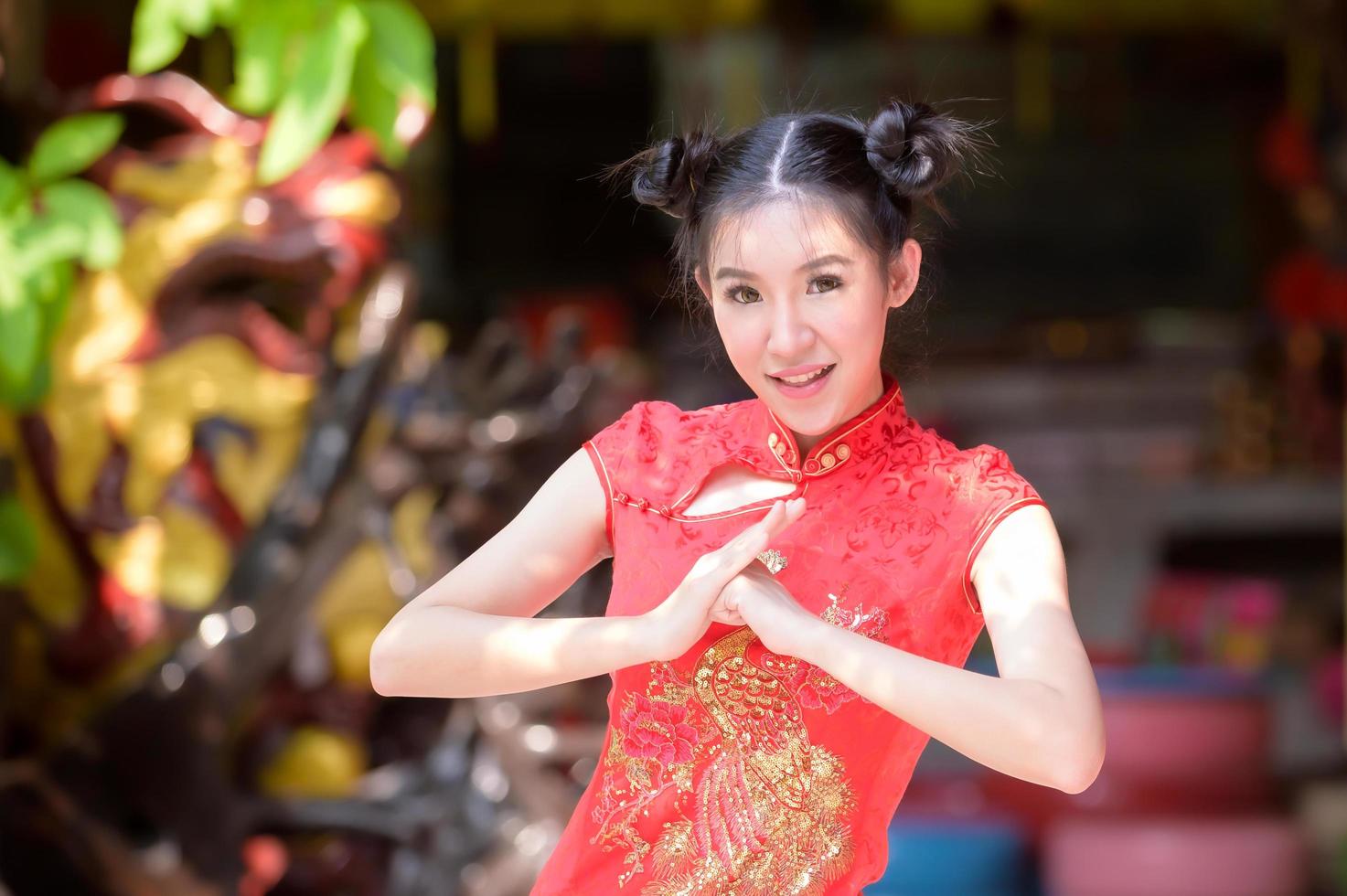 una bella donna asiatica scatta una foto in costume cinese, mostrando un tradizionale saluto per il capodanno cinese