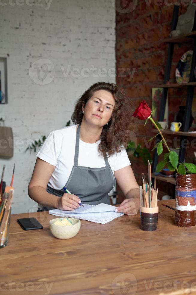 donna artigiana che scrive n taccuino, pianifica la giornata nel diario. bella imprenditrice d'affari foto