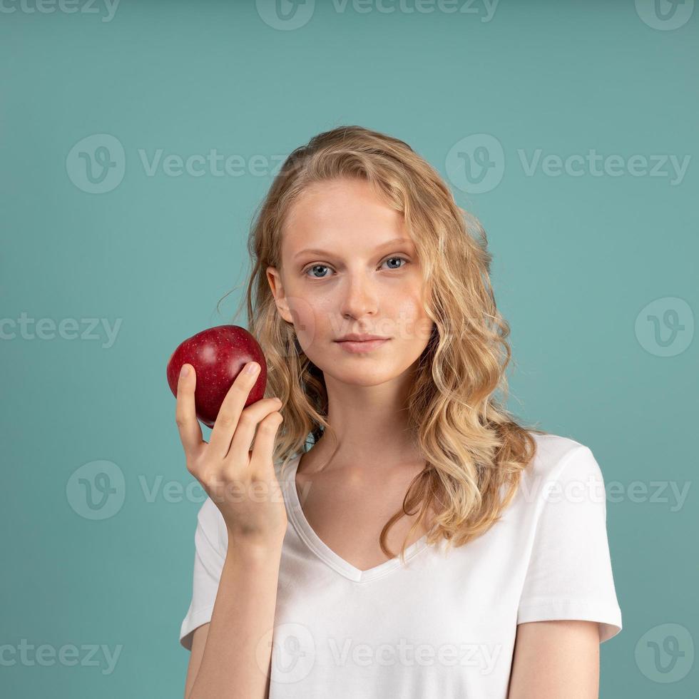 bella giovane donna bionda intelligente seria senza trucco con mela rossa foto