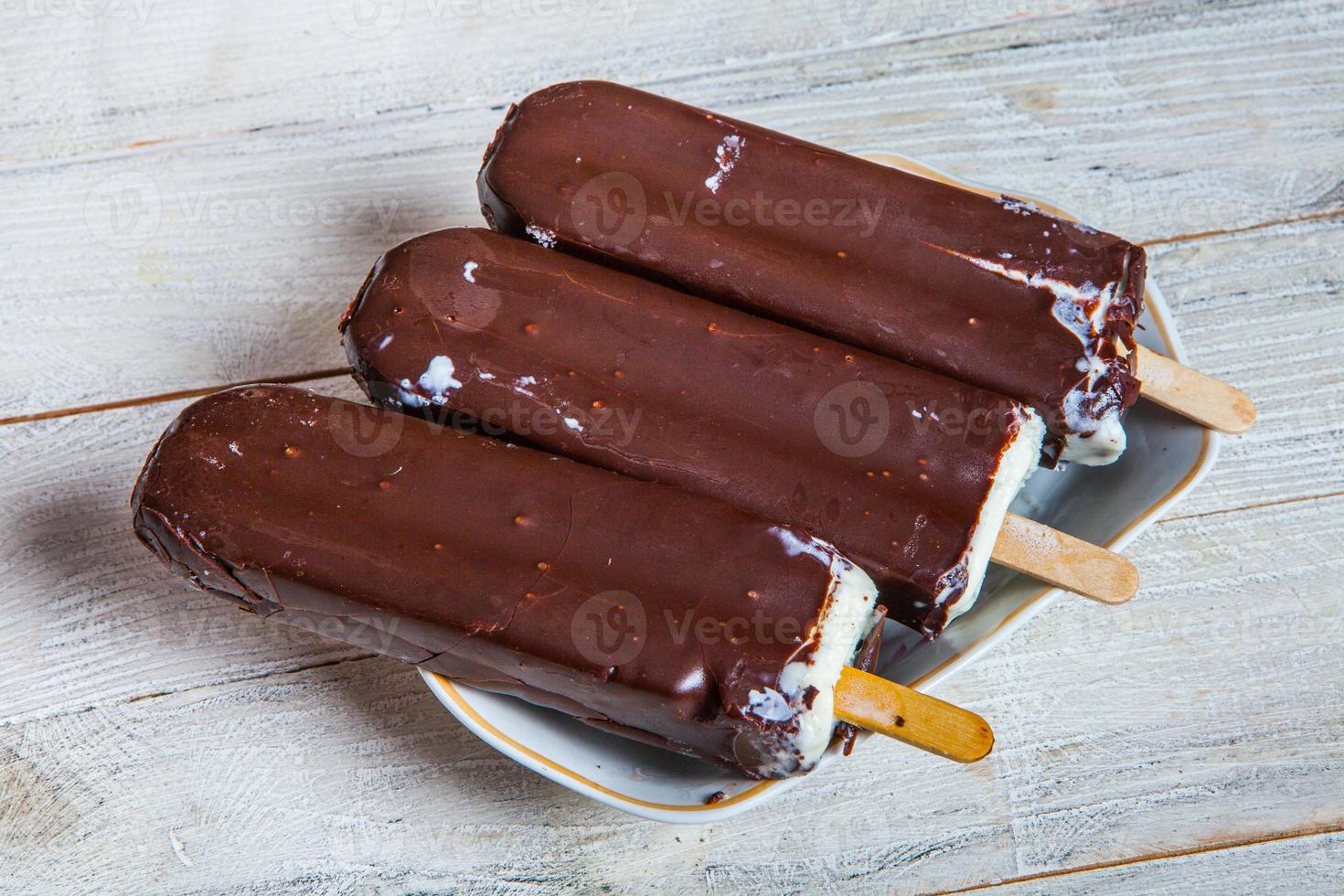primo piano della barra di cioccolato fondente del gelato. gelato ricoperto di cioccolato su fondo di legno foto