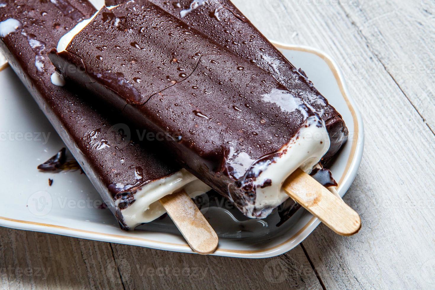 primo piano della barra di cioccolato fondente del gelato. gelato ricoperto di cioccolato su fondo di legno foto