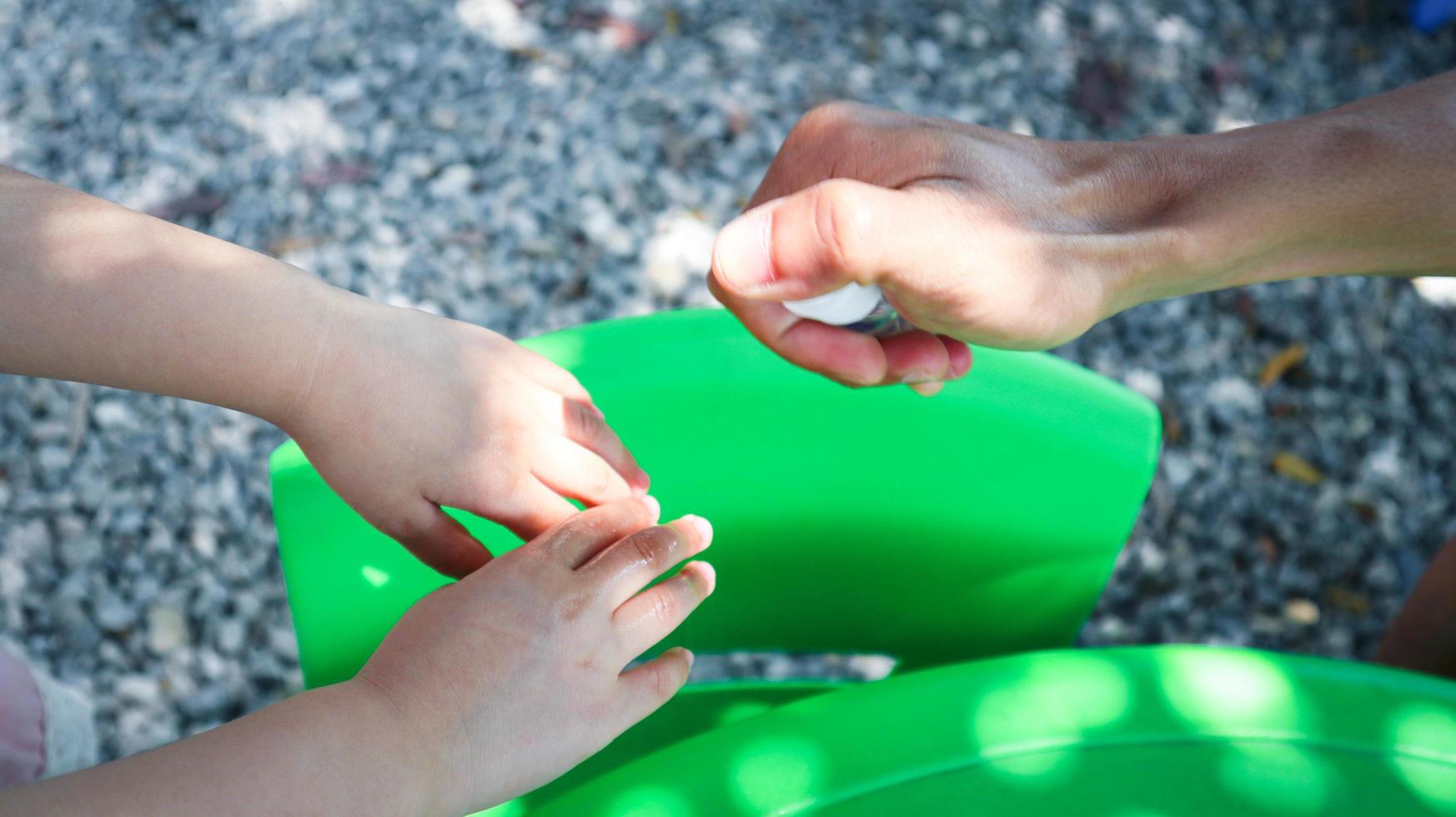 la mano della bambina era intrisa di uno spray alcolico, spruzzato da suo padre. prevenire la diffusione di germi e batteri ed evitare le infezioni da coronavirus. concetto di igiene per bambini foto