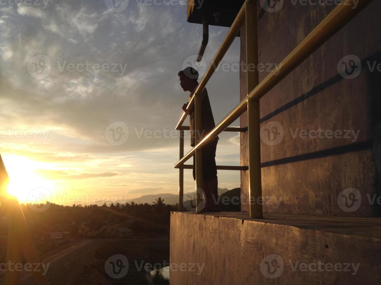 una vista posteriore di un uomo su uno sfondo di cielo arancione foto
