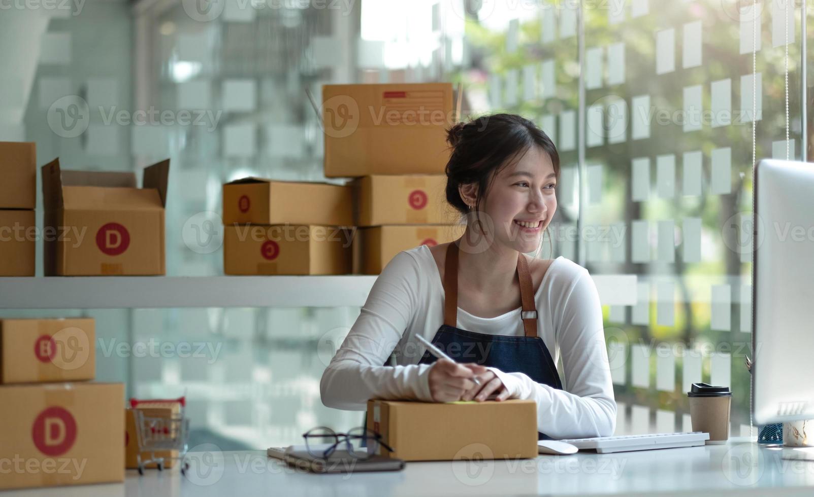 imprenditore asiatico di piccole imprese sme scrivendo l'indirizzo su una scatola di cartone sul posto di lavoro imprenditore di piccole imprese sme, lavorando con la scatola a casa. foto