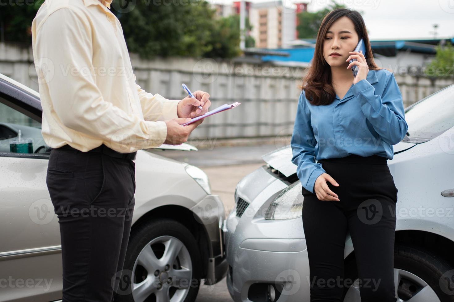 l'autista di donne asiatiche parla con l'agente assicurativo per l'esame dell'auto danneggiata e il controllo del cliente sul modulo di richiesta di denuncia dopo un incidente. concetto di assicurazione e incidenti stradali. foto