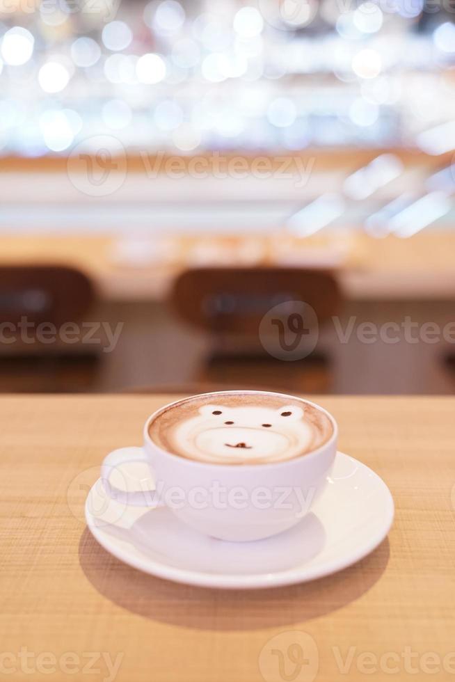 carino orso latte caldo caffè in tazza bianca sul tavolo di legno, leggere per servire. foto