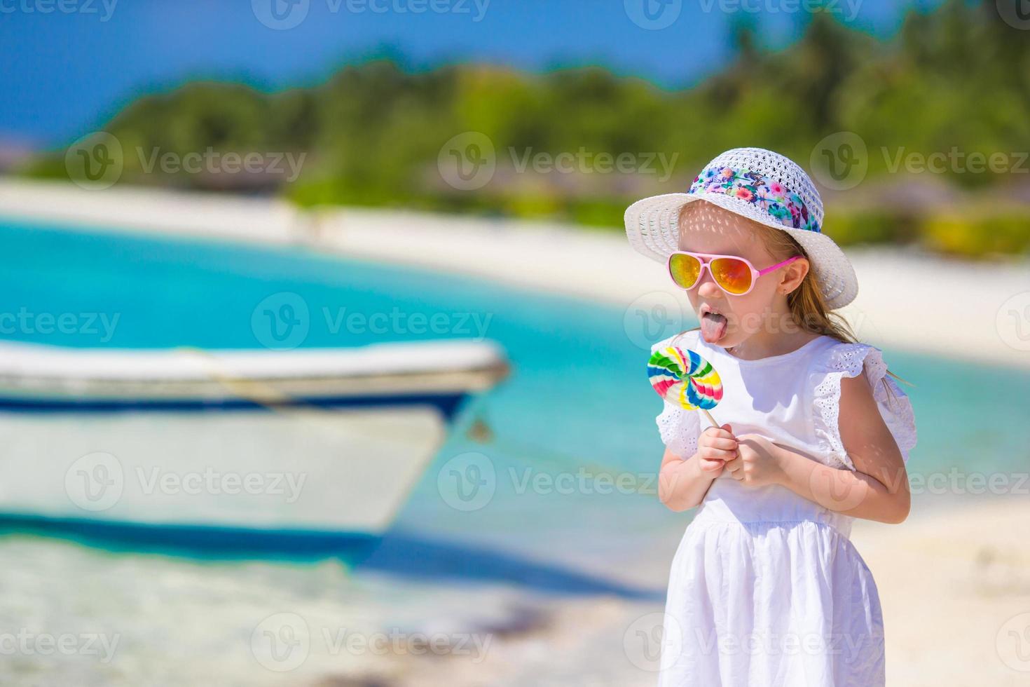 adorabile bambina con lecca-lecca sulla spiaggia tropicale foto