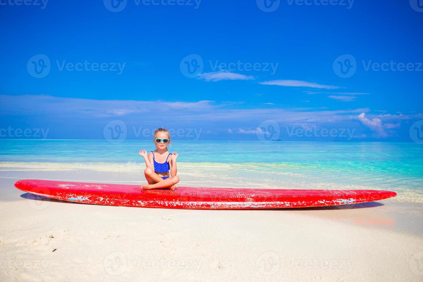 bambina in posizione yoga meditando sulla tavola da surf foto