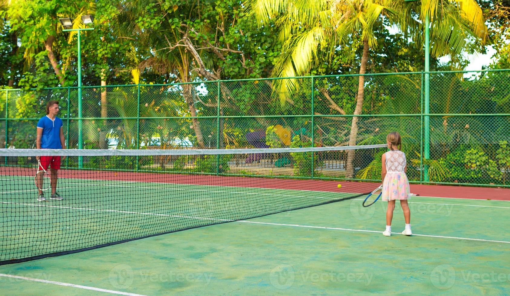 bambina che gioca a tennis con suo padre in campo foto