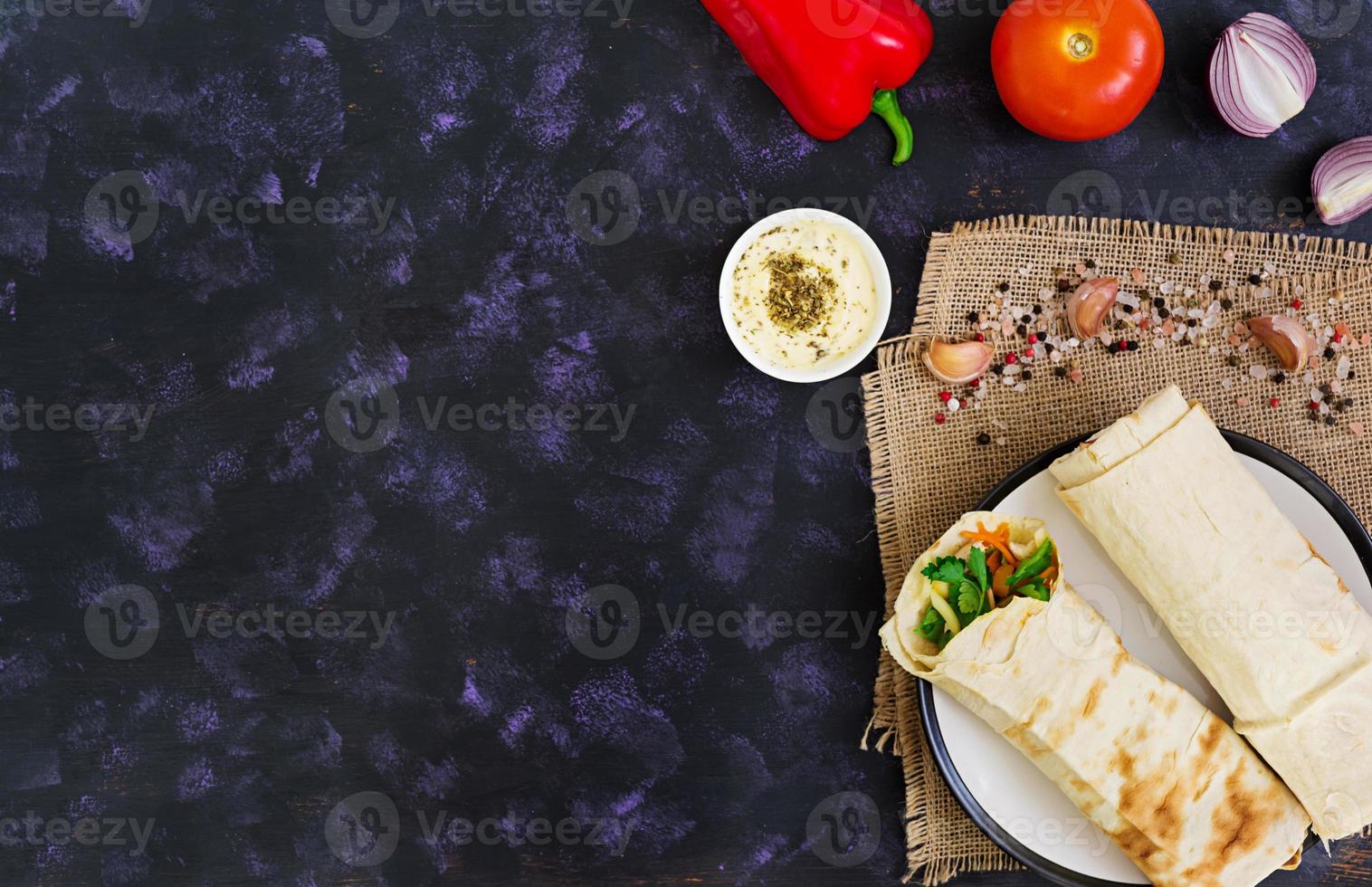 panino shawarma con ingredienti su sfondo scuro. vista dall'alto foto