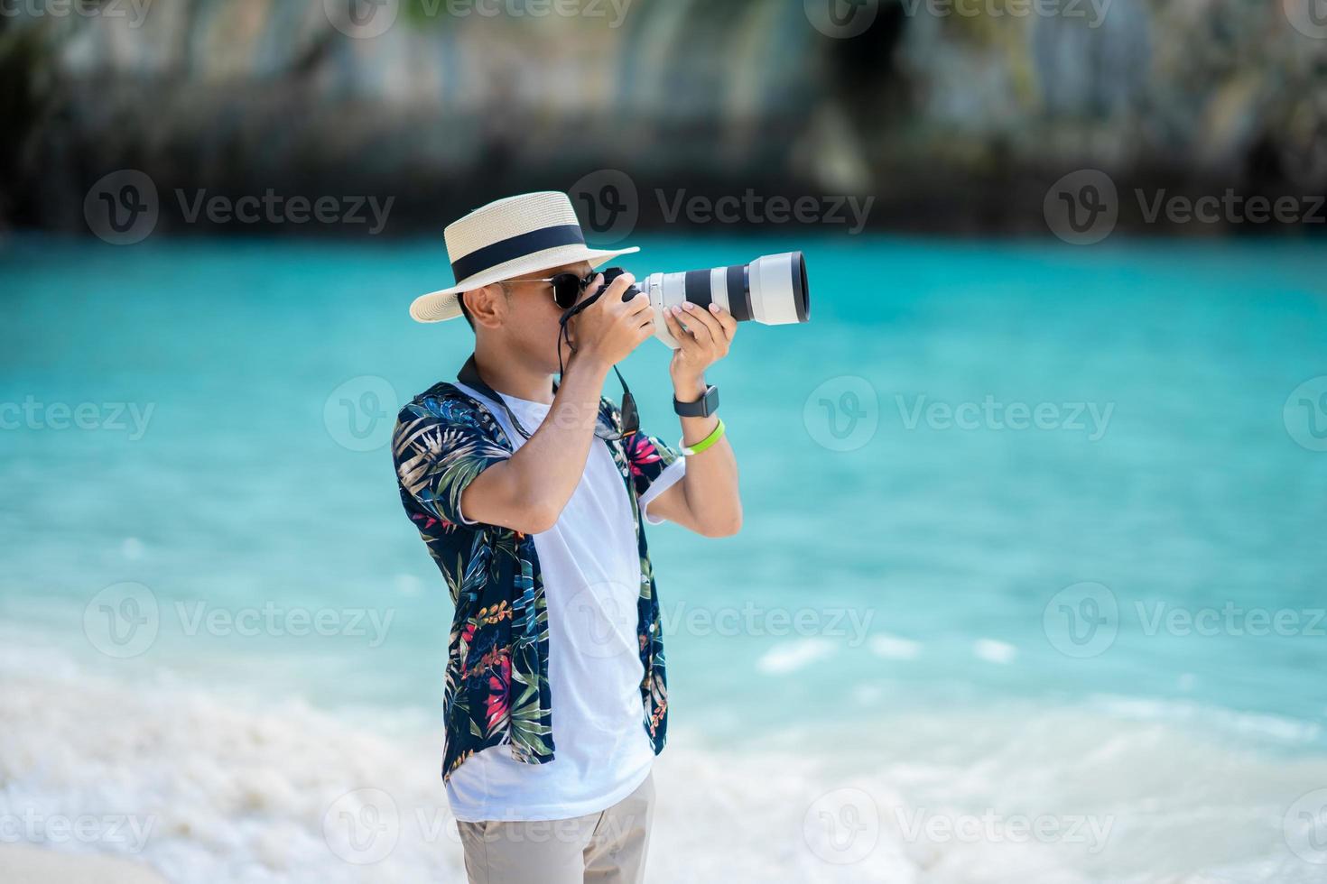 turista maschio che utilizza una macchina fotografica per scattare foto del mare in tailandia