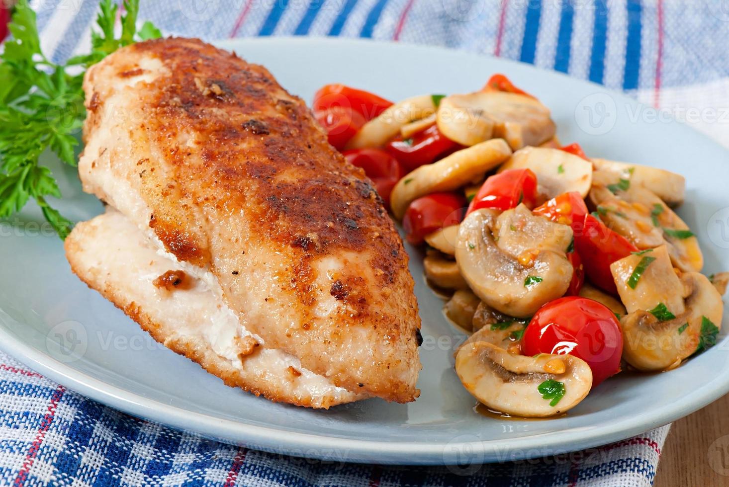 filetto di pollo nel pangrattato croccante guarnito con funghi e pomodori foto