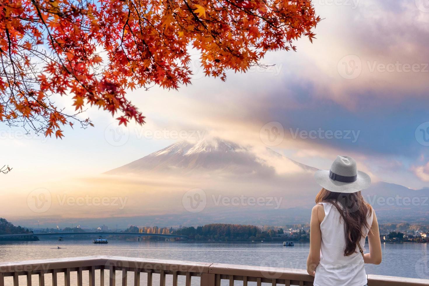 giovane donna asiatica in piedi sul balcone di legno guardando il monte fuji-san attraverso la nebbia con copertura in acero rosso al mattino foto