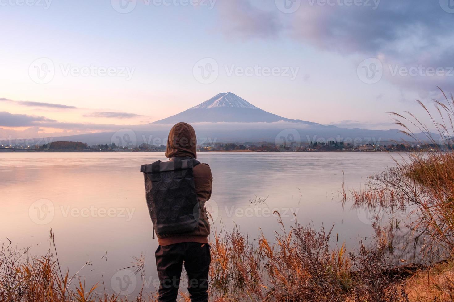 il giovane asiatico sta guardando il monte fuji sul lago kawaguchiko all'alba foto