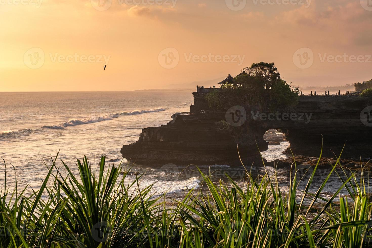 tempio di pura batu bolong sulla scogliera di roccia con albero sulla costa al tramonto foto