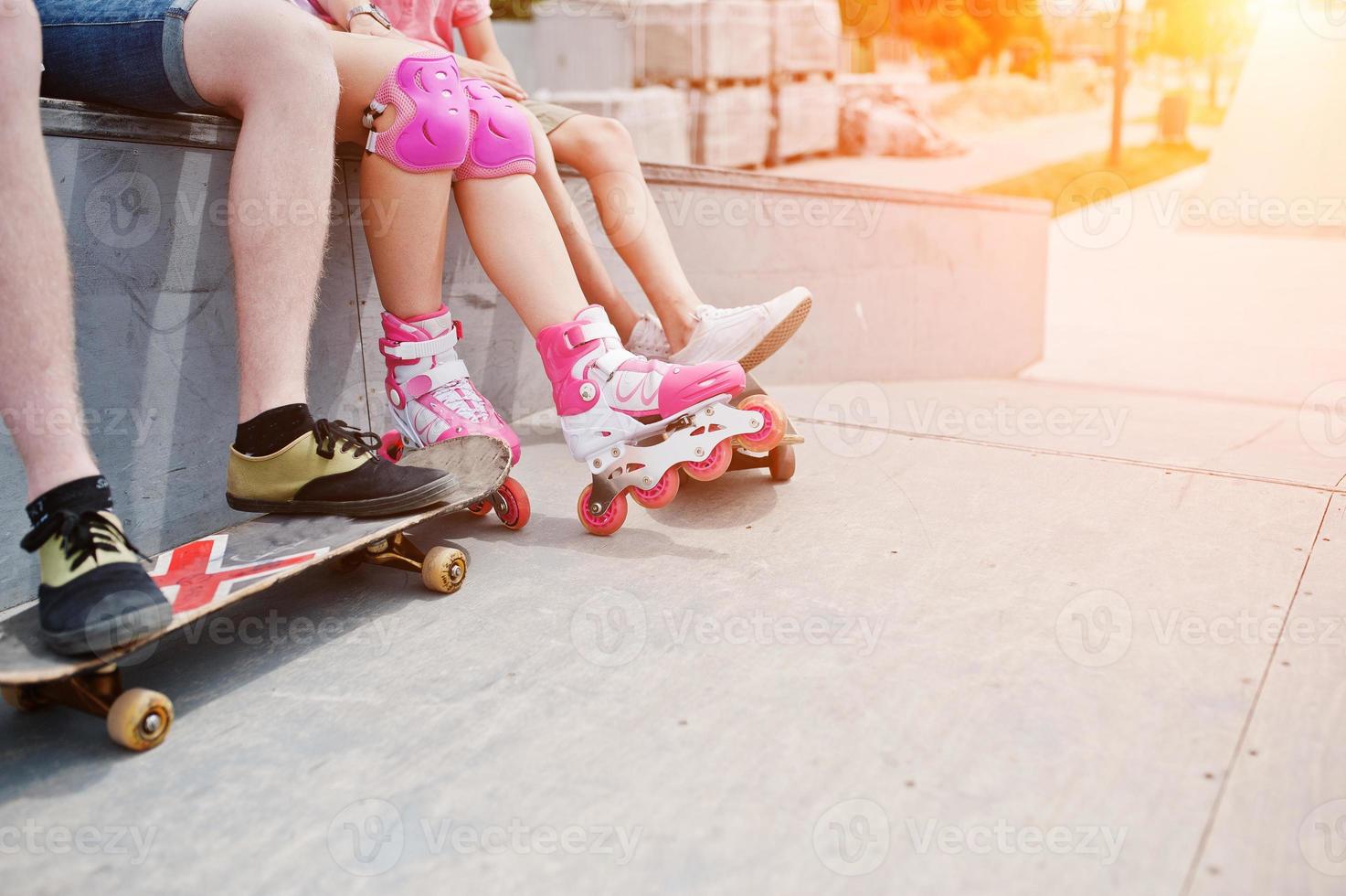 foto ravvicinata di gambe maschili su skateboard e gambe femminili in pattini e protezione.