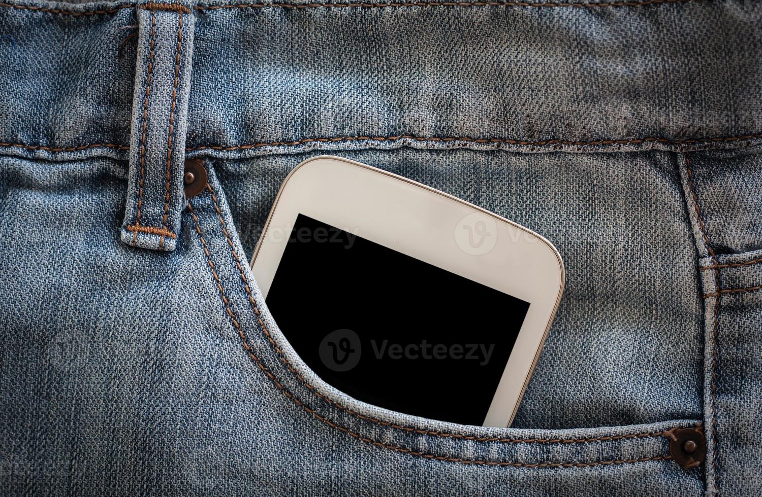 cellulare in tasca dei jeans con schermo nero foto