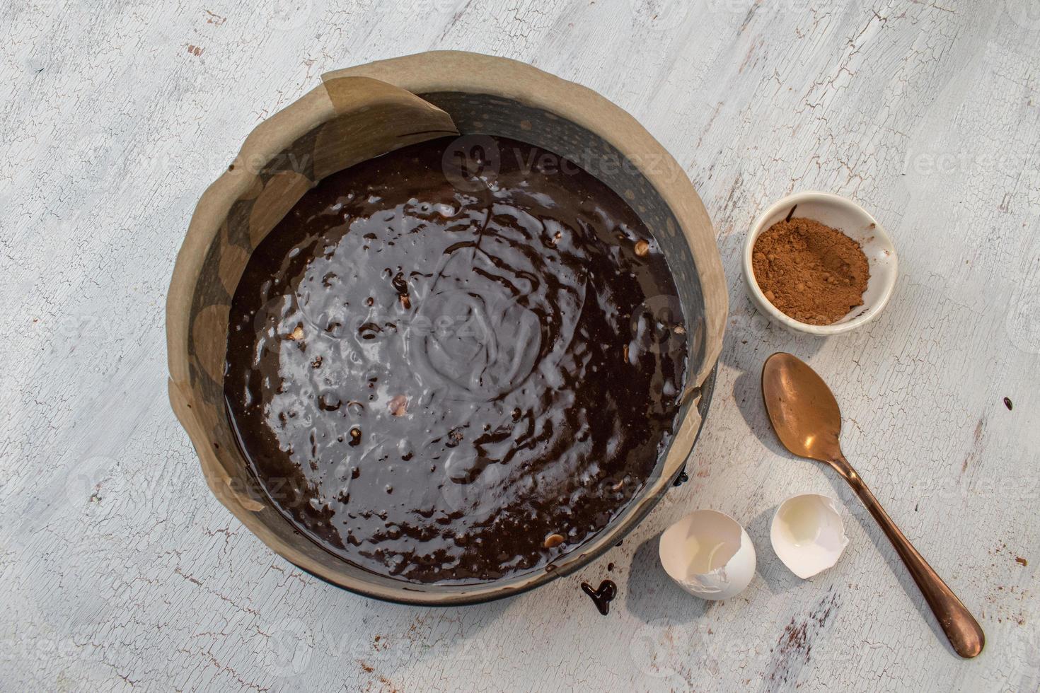 pastella per brownie in uno stampo tondo con carta oleata e ingredienti distesi foto