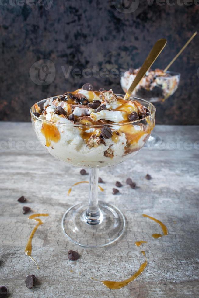 Dessert di budino alla vaniglia e cioccolato condito con caramello e gocce di cioccolato foto