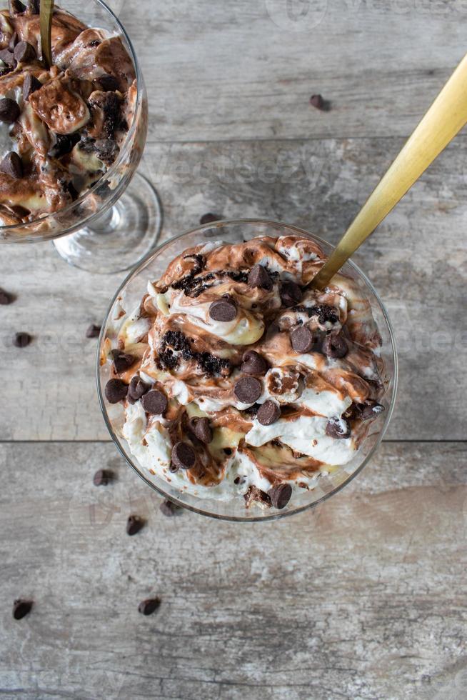 Dessert di budino alla vaniglia e cioccolato condito con caramello e gocce di cioccolato flat lay foto