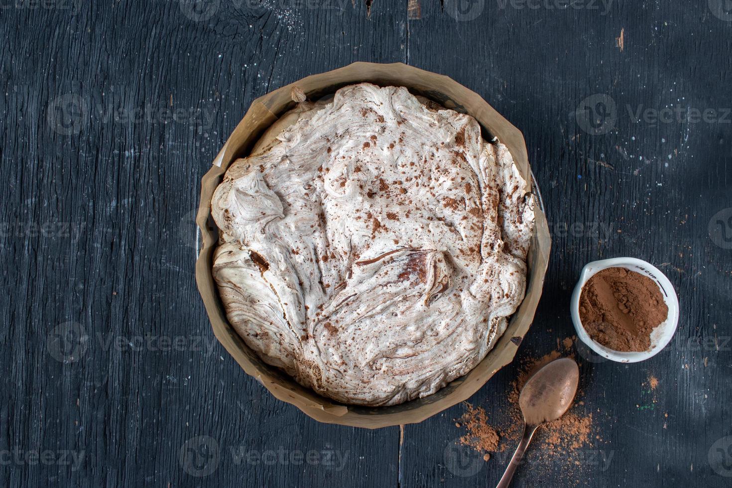 brownie tondo al forno condito con meringa e vortici di cioccolato piatto foto