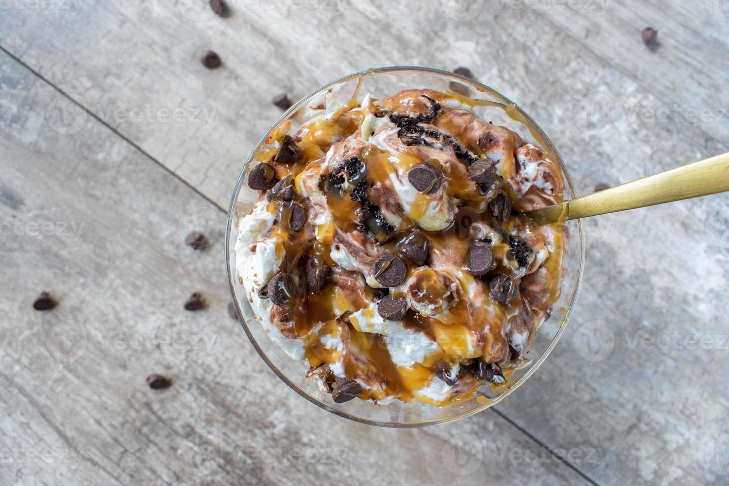 Dessert di budino alla vaniglia e cioccolato condito con caramello e gocce di cioccolato flat lay foto