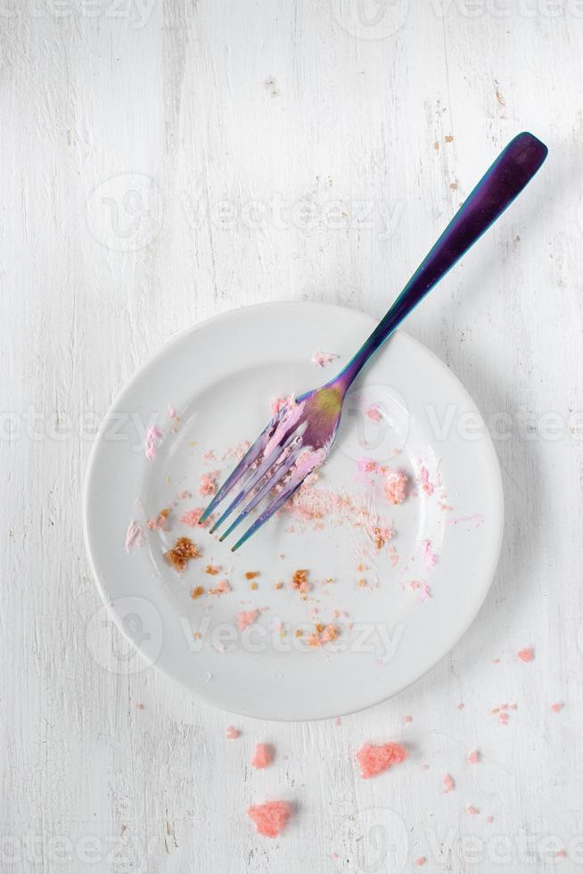 piatto vuoto di briciole di torta di compleanno con forchetta piatta foto