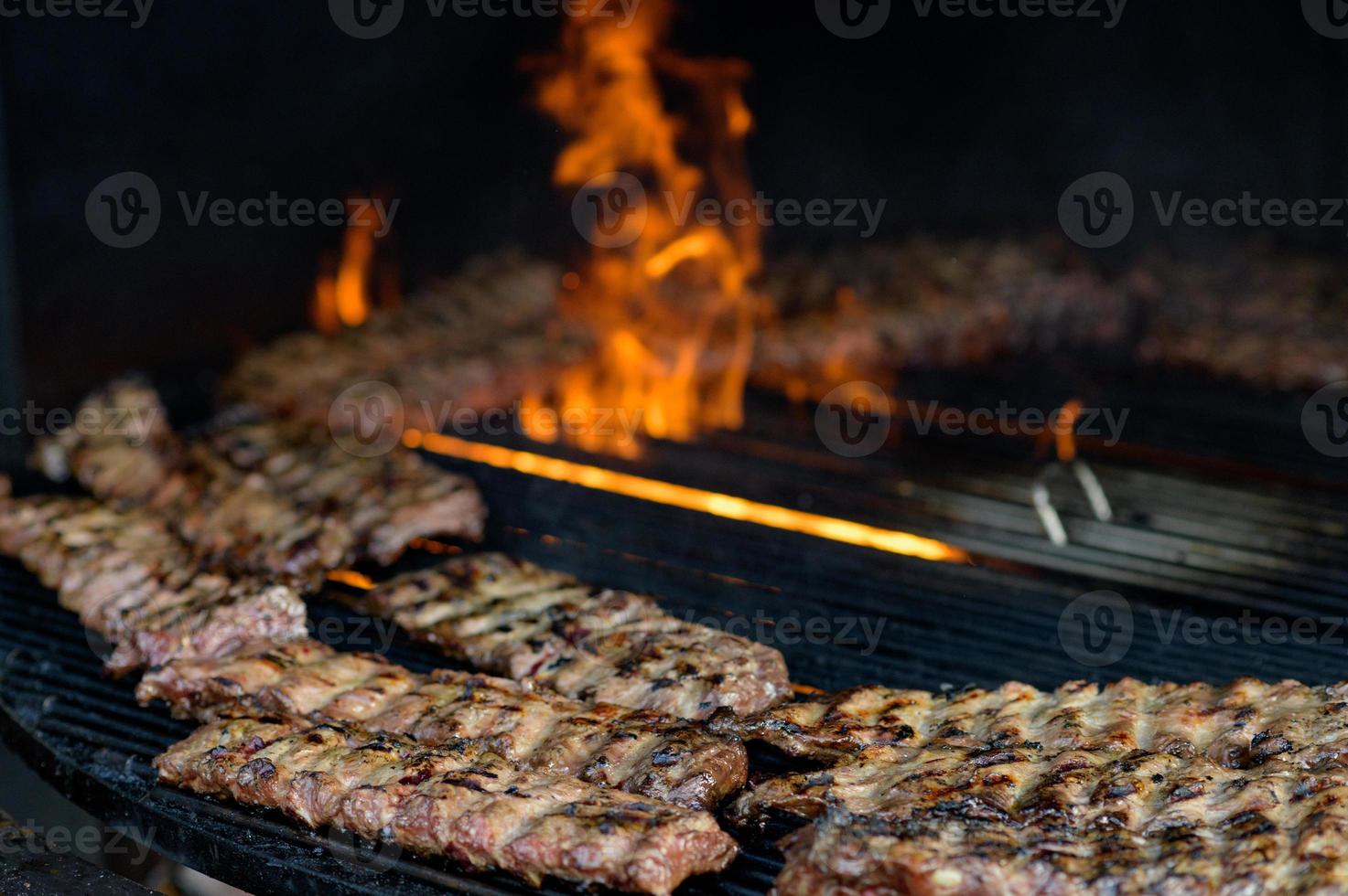 salsiccia grigliata con aggiunta di erbe e verdure sulla piastra grill, all'aperto. grigliate, barbecue, barbecue foto