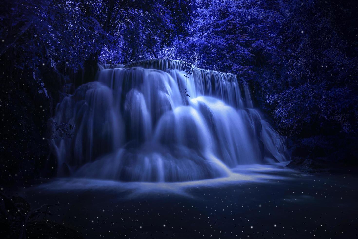 bellissimo scenario naturale della cascata colorato in una giungla fantasy tropicale profonda di notte foto