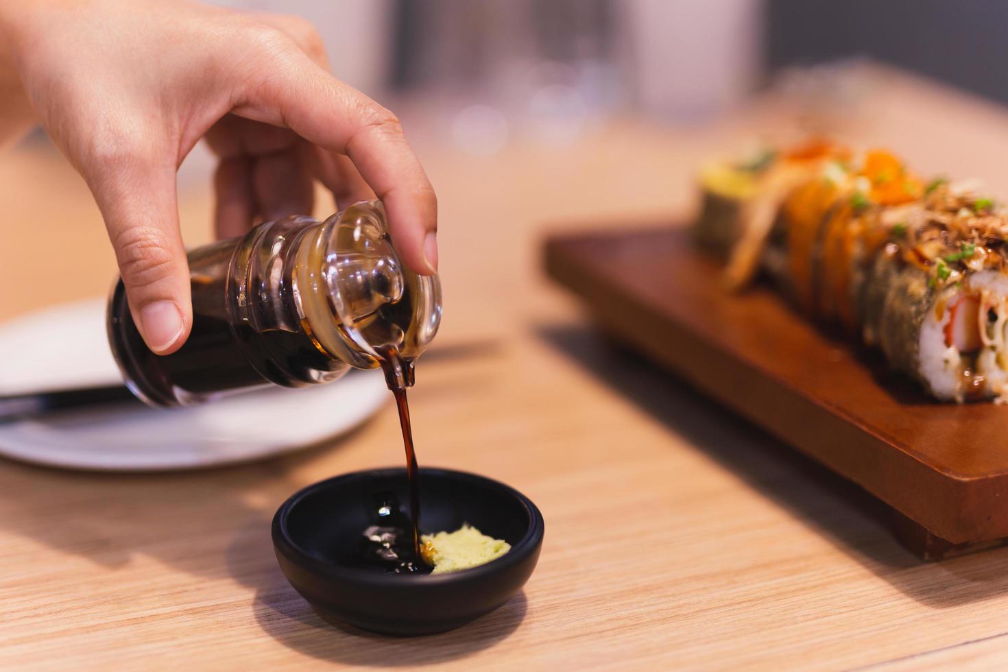 donne che versano salsa shoyu sulla ciotola di immersione con wasabi. foto