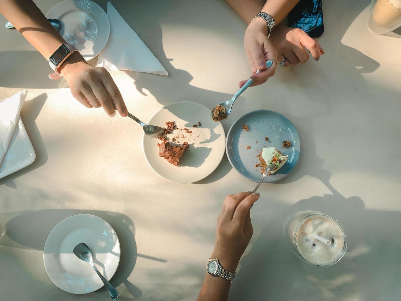 la mano con il cucchiaio si diverte a mangiare la torta nella caffetteria. vista dall'alto foto