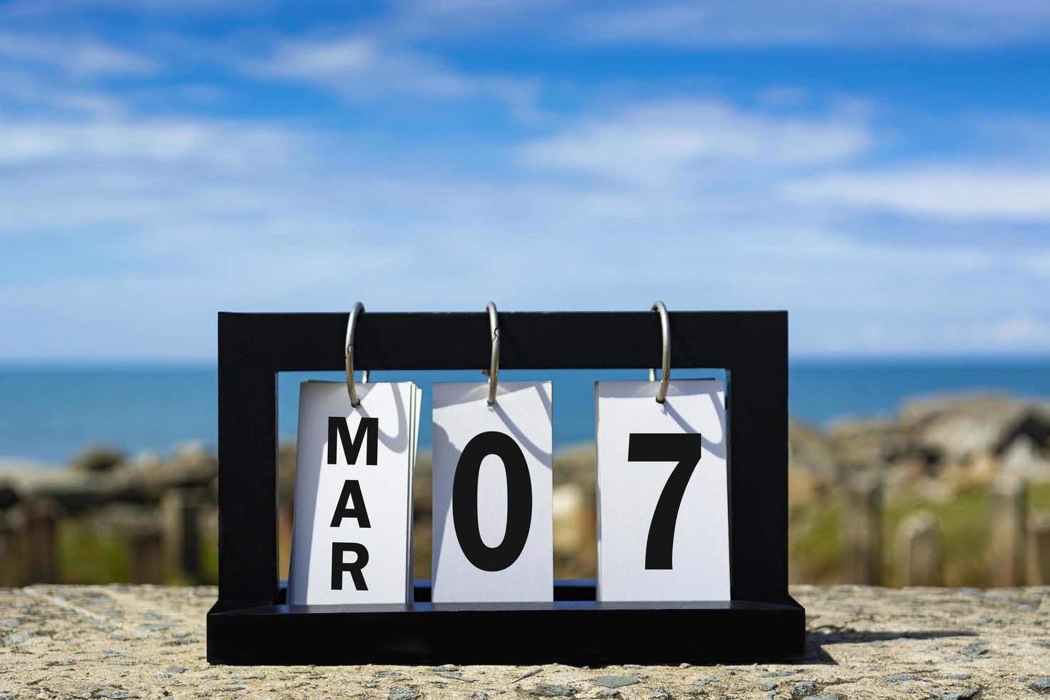 mar 07 testo della data del calendario su telaio in legno con sfondo sfocato dell'oceano foto